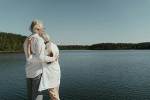 Senior couple hugging by the river, enjoying scenic views and peaceful retirement lifestyle in Tennessee.