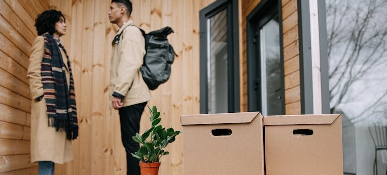 couple standing outside with moving boxes in front of a home