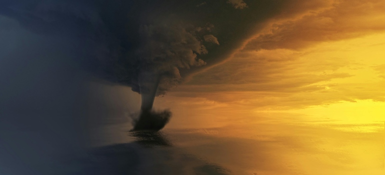 Waterspout over the ocean at sunset, hinting at the Costs of Moving to Florida During Hurricane Season.