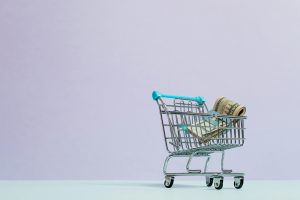 A mini shopping cart filled with money.