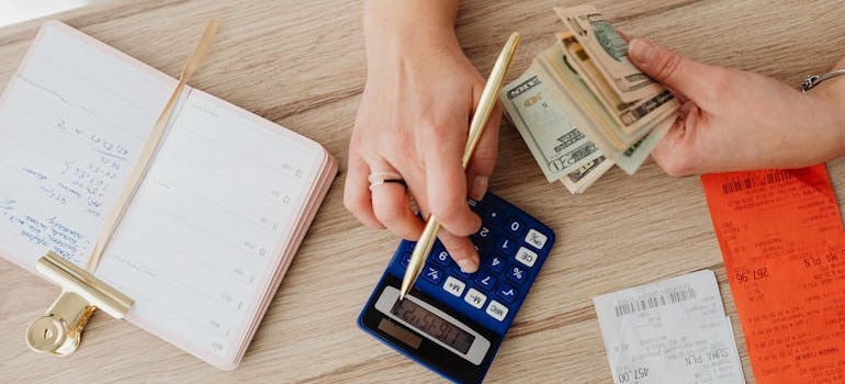 person calculating the cost of hiring a moving broker