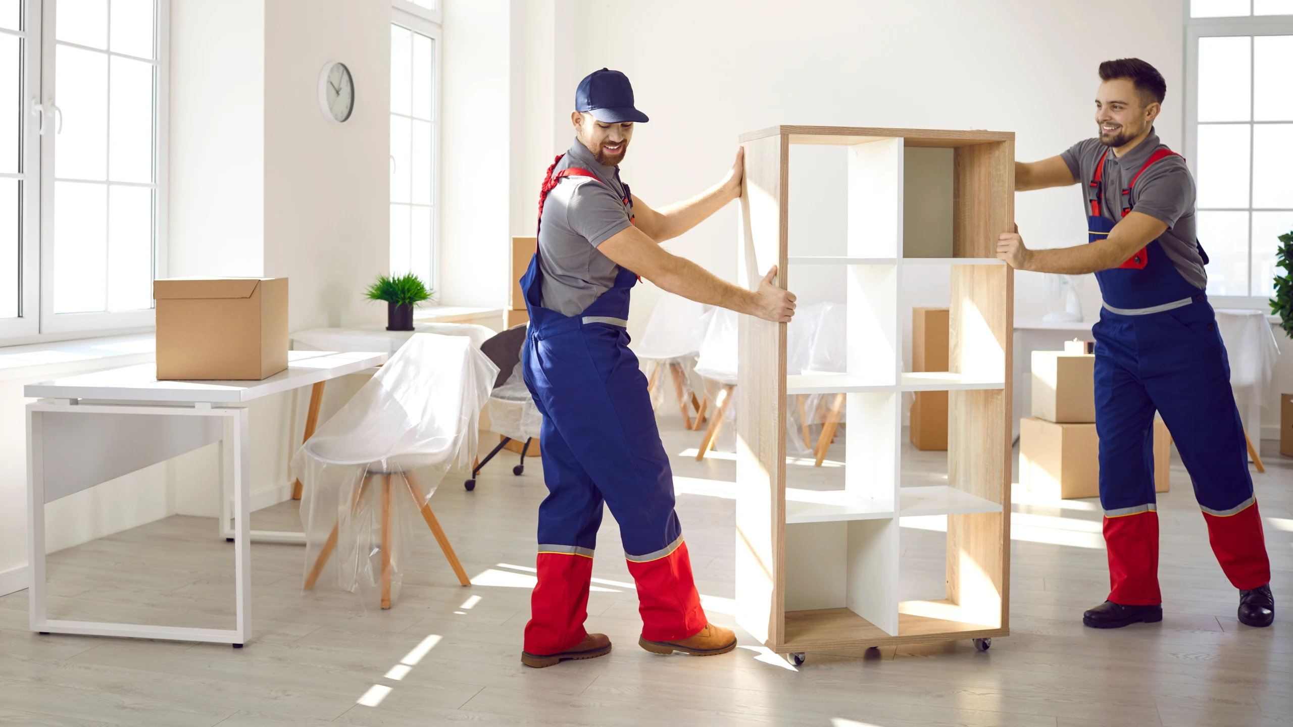 Professional corporate relocation service providers wrap an office chair in protective plastic.