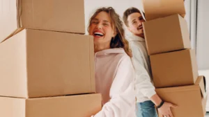 Young couple moves boxes happily after learning how to make moving less stressful.