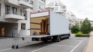Moving truck with an open cargo hull, parked on a city street.