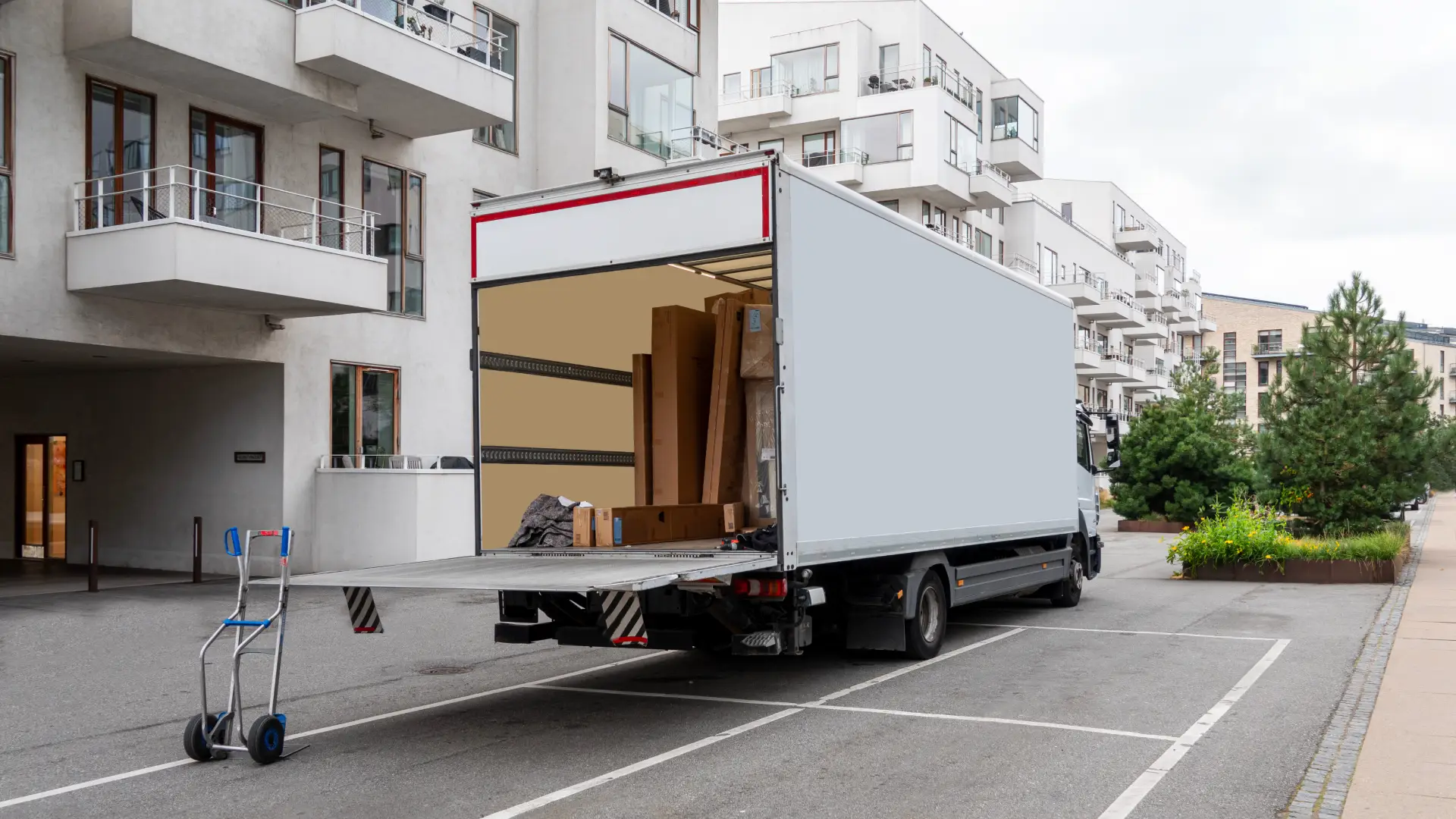 Moving truck with an open cargo hull, parked on a city street.